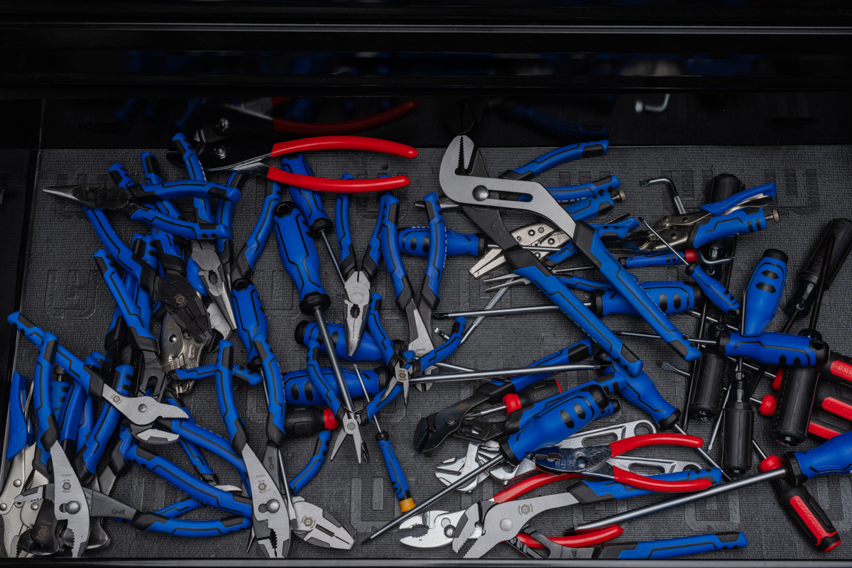 Tool drawer filled with a disorganized pile of pliers and mixed tools — the chaos most mechanics deal with after driving