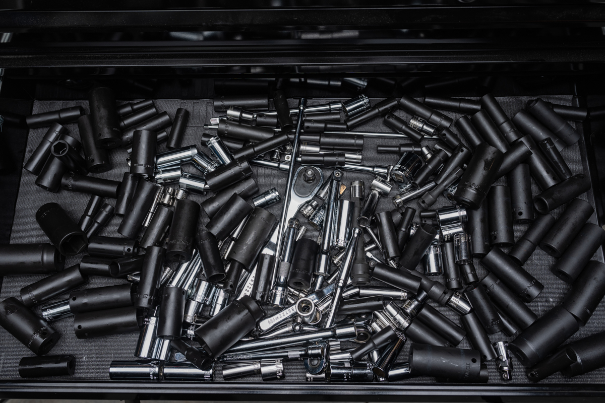 Drawer filled with a disorganized pile of black sockets and extensions