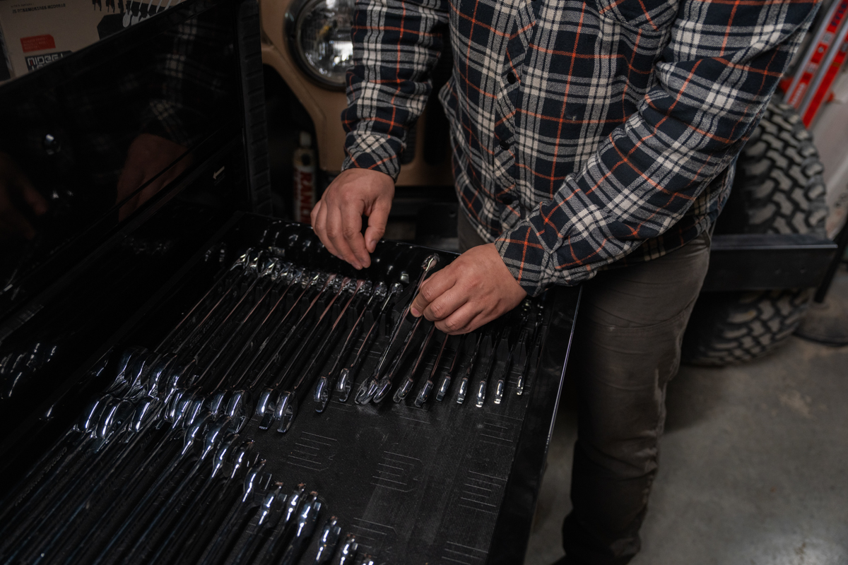Focus on a mechanic's hand retrieving a chrome wrench from the vertical organizer
