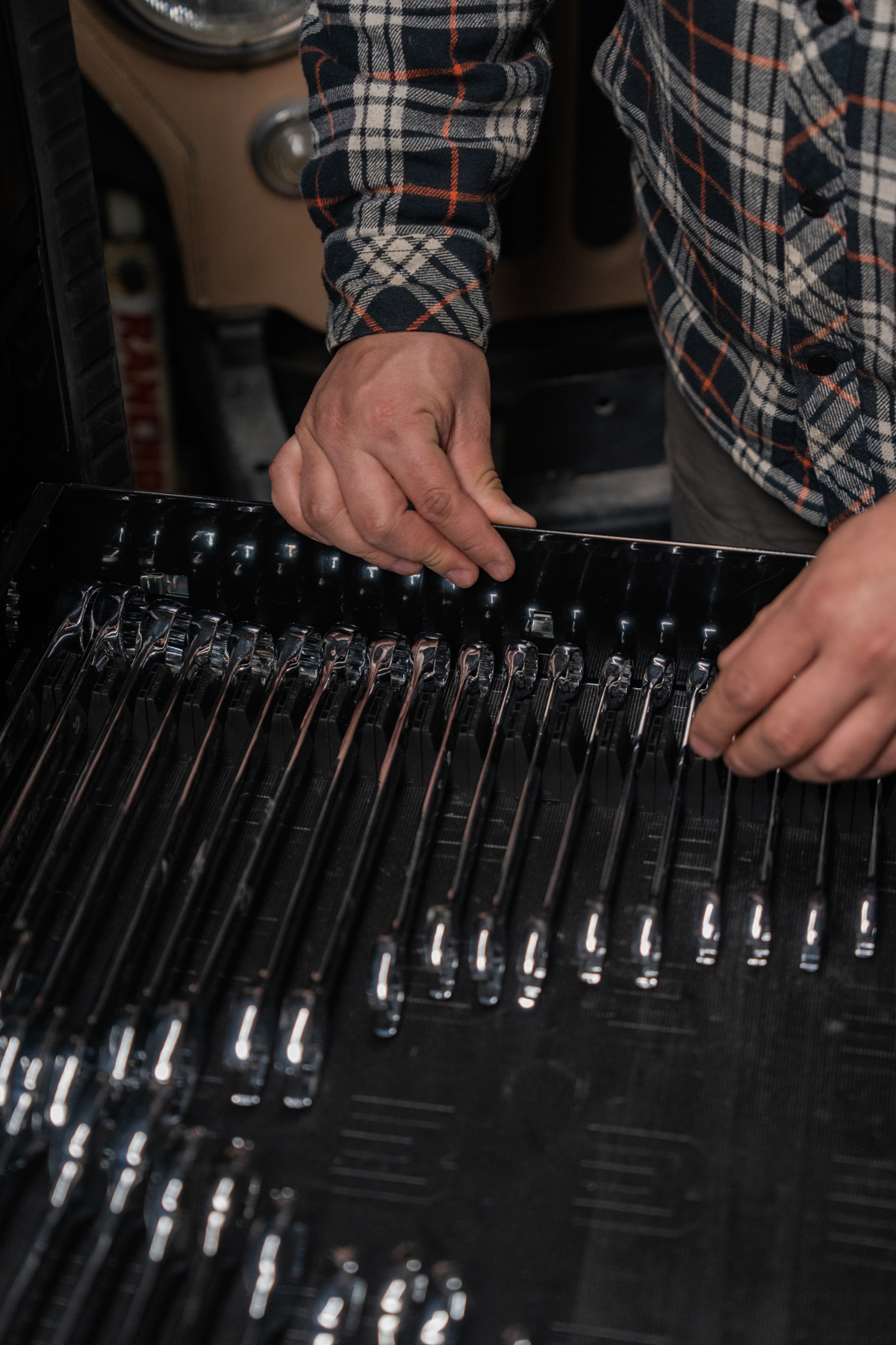 Close-up of hands adjusting modular wrench organizers in a tool drawer