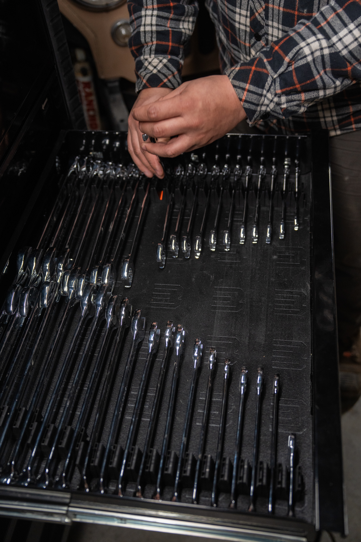 Hands arranging wrenches into modular organizer slots for custom layout