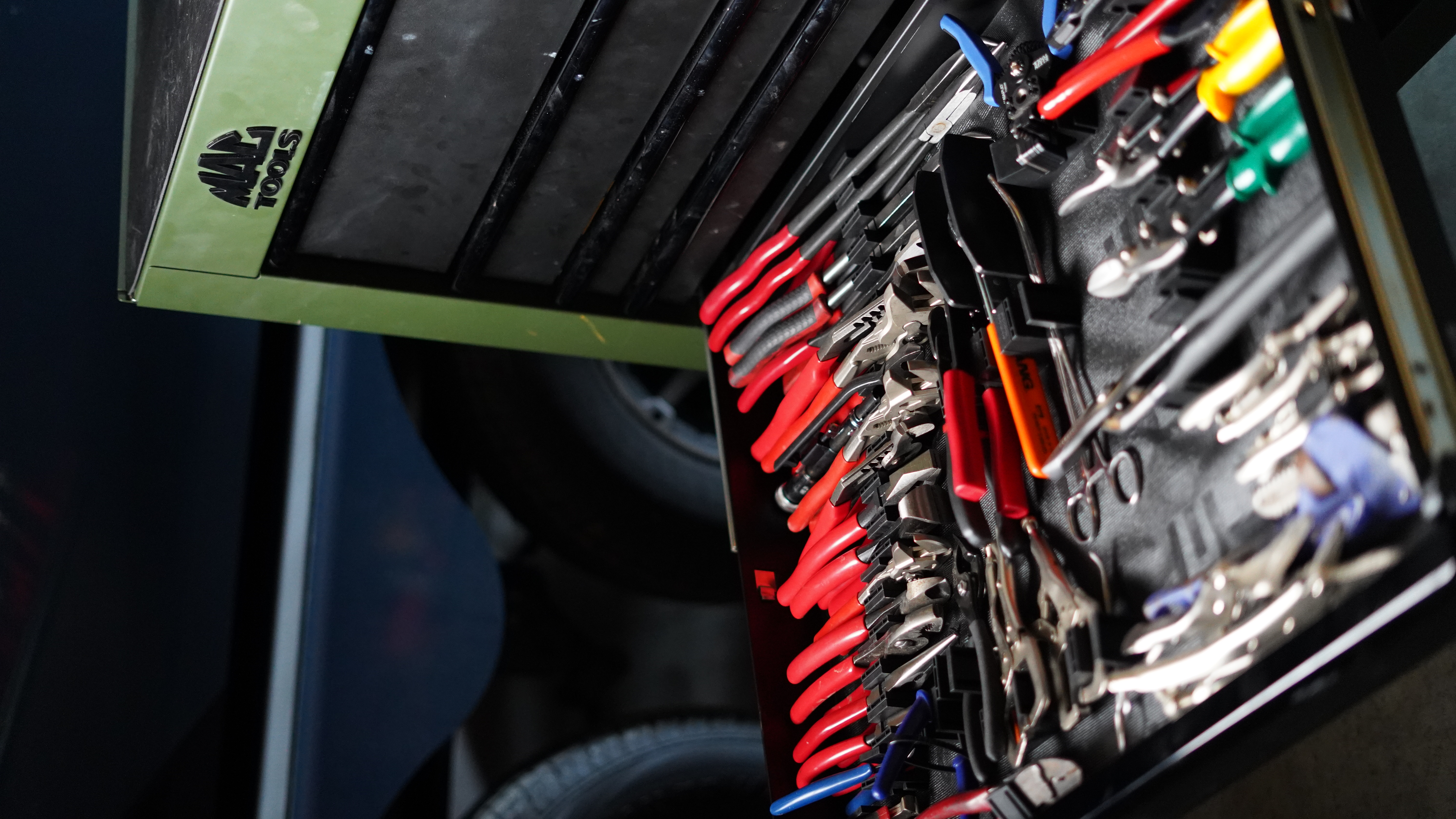 High-angle view of green Mac Tools chest drawer filled with red-handled pliers organized upright